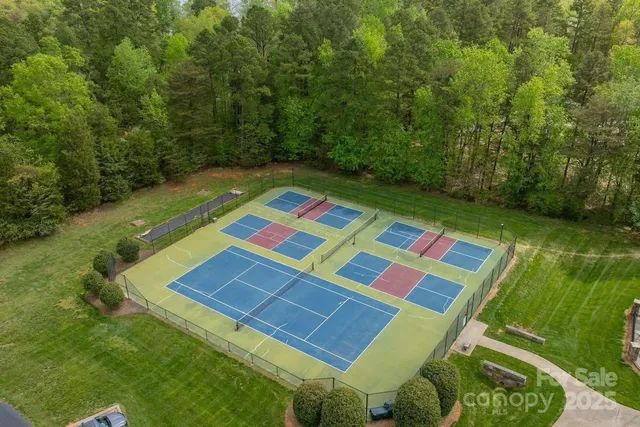 a view of a tennis ground with a white house