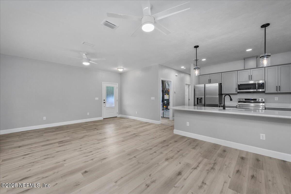 108 Pamela Street Interlachen, FL 32148 - Photo 21 of 31 wooden floor in an empty room with kitchen view