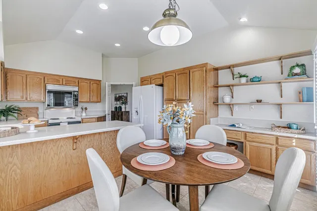 a dining room with stainless steel appliances a table and chairs
