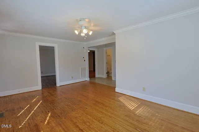 a view of an empty room with wooden floor and a chandelier