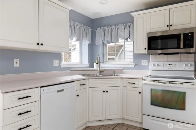 a kitchen with white cabinets appliances and a window