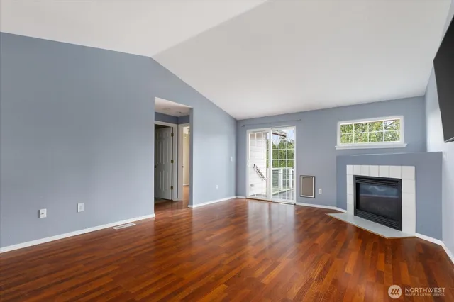 a view of an empty room with wooden floor and a fireplace