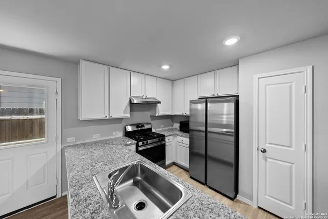 a kitchen with a refrigerator sink and cabinets