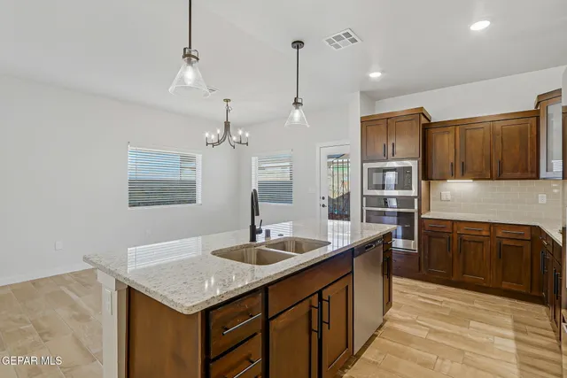 a kitchen with granite countertop a sink cabinets and stainless steel appliances