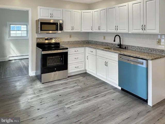 a kitchen with stainless steel appliances granite countertop a stove a sink and white cabinets