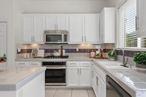 a kitchen with stainless steel appliances granite countertop a sink stove oven and white cabinets