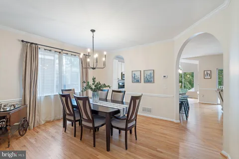 a kitchen with stainless steel appliances granite countertop a sink a stove a refrigerator cabinets and a dining table