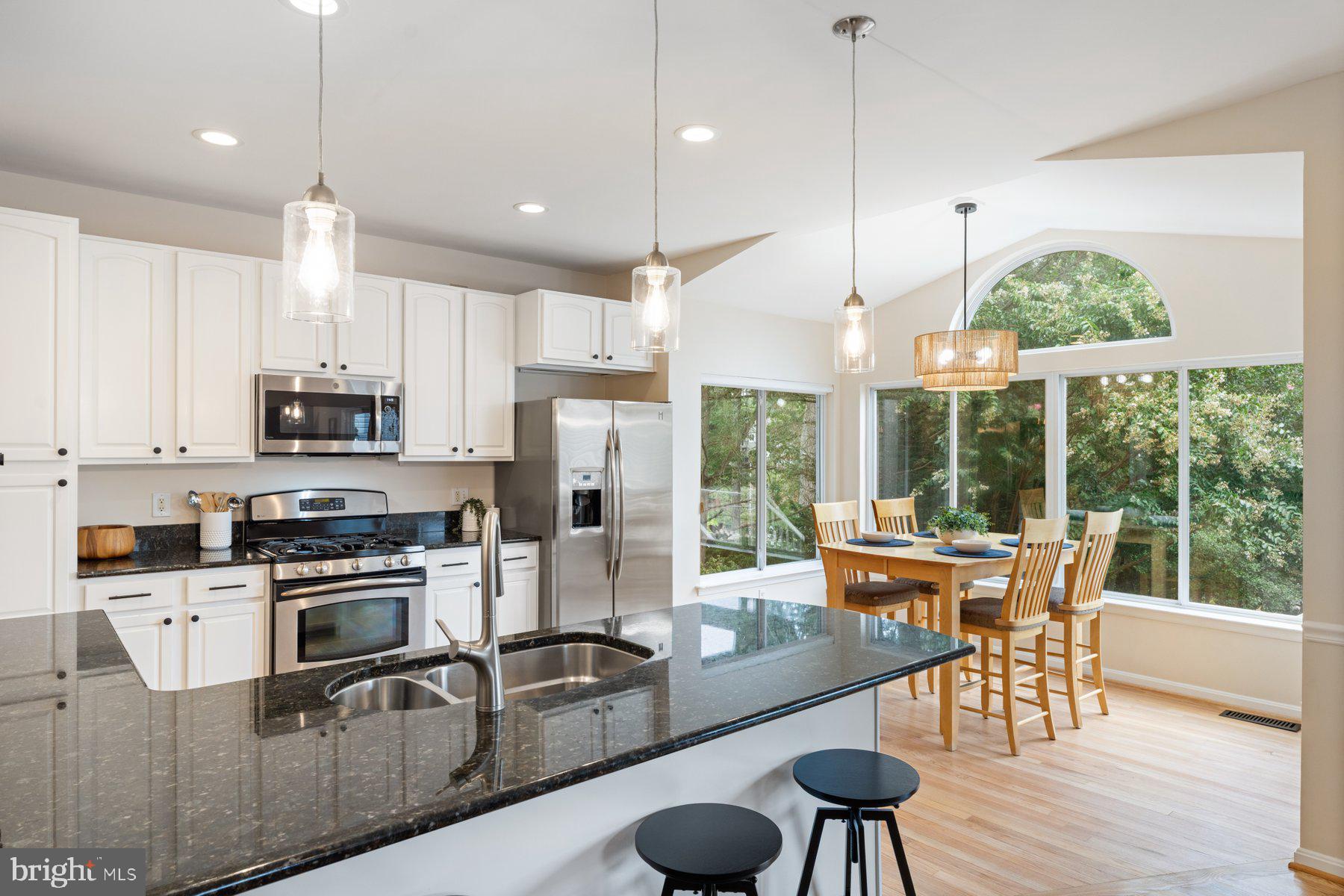359 Valley Stream Road Severna Park, MD 21146 - Photo 13 of 55 a kitchen with stainless steel appliances granite countertop a stove a refrigerator a kitchen island a dining table and chairs with wooden floor