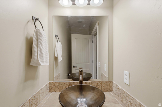 2567 West Rim Rock Drive Stockton, UT 84071 - Photo 22 of 64 Bathroom vanity featuring a vessel sink, dark bronze faucet, and a large mirror