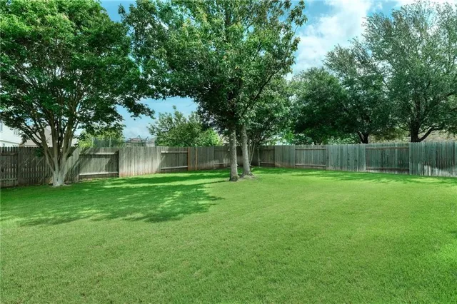 a view of a backyard with large trees and wooden fence