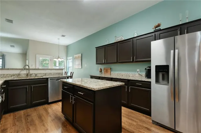 a kitchen with stainless steel appliances granite countertop a stove refrigerator sink and microwave