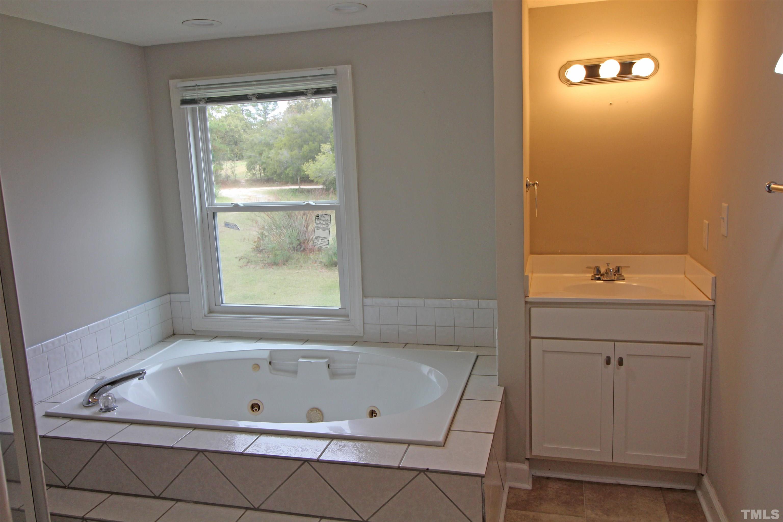 3202 Old Stage Road North Coats, NC 27521 - Photo 12 of 20 a bathroom with a tub a sink and a window