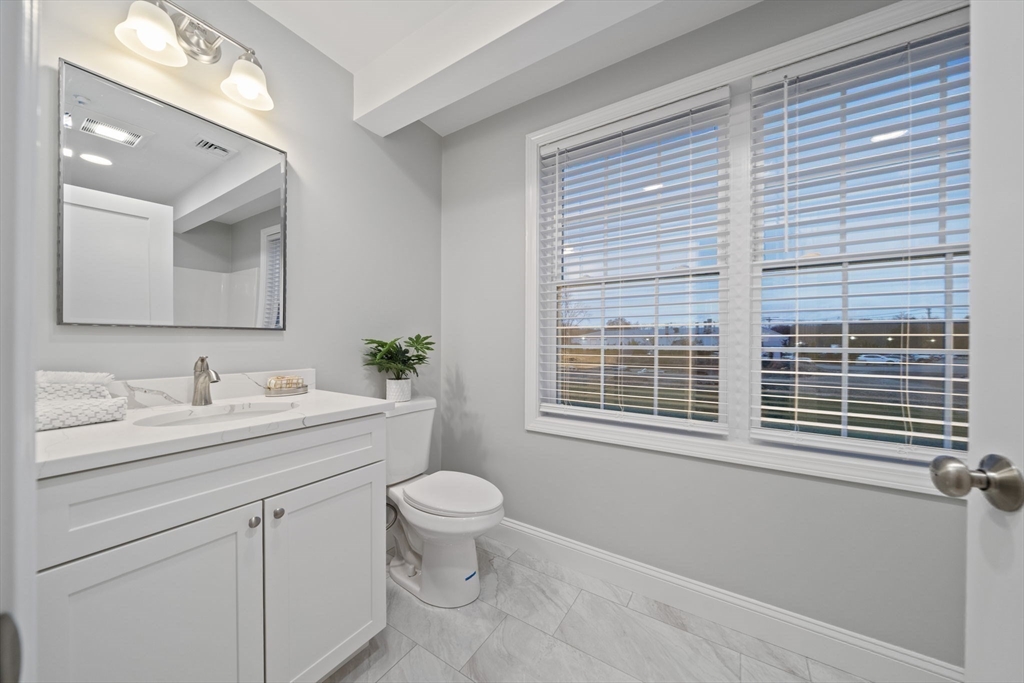 8 Simmonds Boulevard, Unit 8 Randolph, MA 02368 - Photo 13 of 28 a bathroom with a granite countertop sink toilet a large mirror and a window