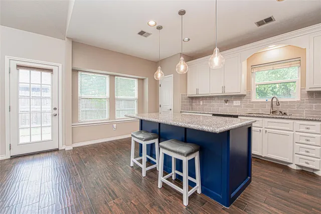 a open kitchen with granite countertop a sink dishwasher a dining table and chairs with wooden floor