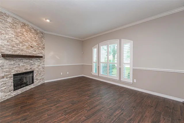 an empty room with wooden floor fireplace and windows