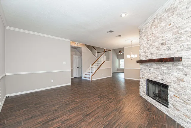 an empty room with wooden floor staircase and fireplace