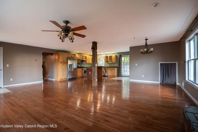 a view of a room with wooden floor a ceiling fan and windows