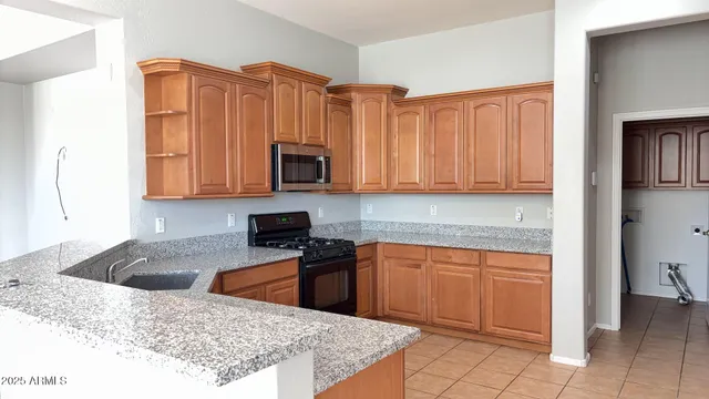 a kitchen with stainless steel appliances granite countertop a stove top oven a sink dishwasher and a microwave oven on the blue kitchen countertops