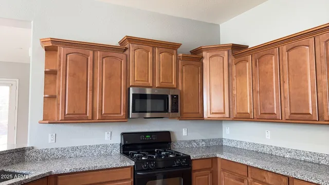 a kitchen with stainless steel appliances granite countertop a refrigerator a stove top oven and a sink with granite countertops