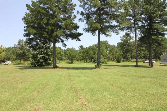 a view of a field with trees in front of house