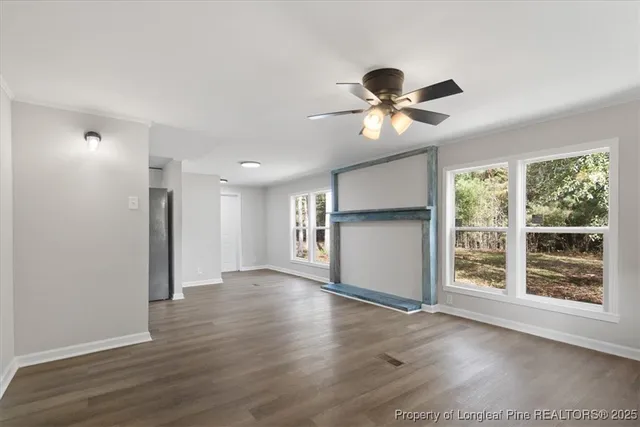 a view of an empty room with a window and wooden floor