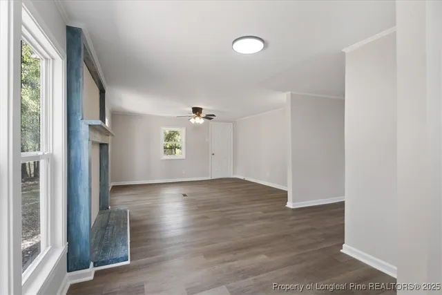 a view of an empty room with a window and wooden floor