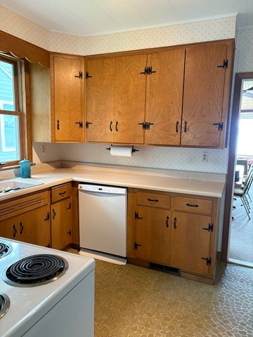 a view of a refrigerator in kitchen and an empty room