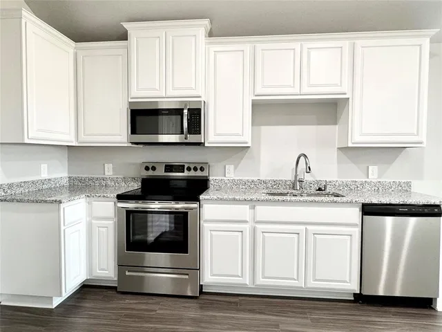 a kitchen with granite countertop white cabinets and a stove a oven with white countertops