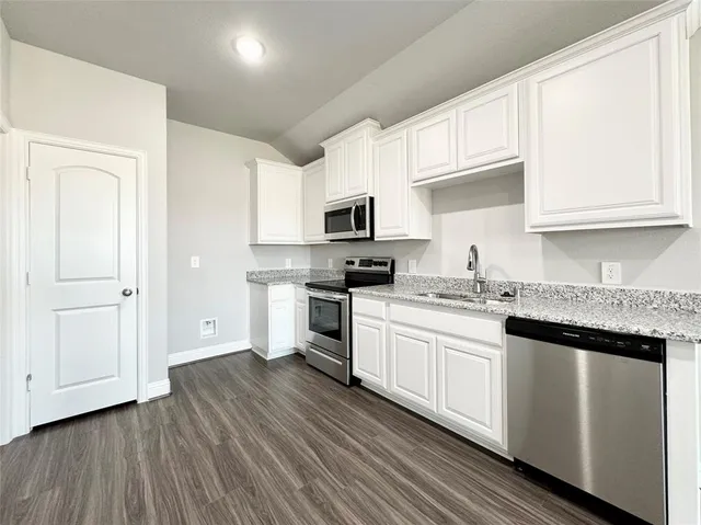 a kitchen with granite countertop a refrigerator and a stove top oven