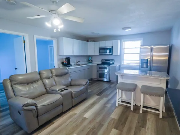 a living room with furniture and a dining table with wooden floor