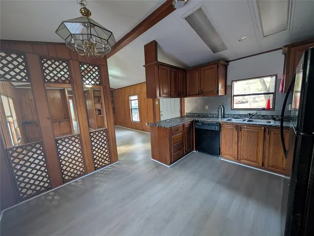 a kitchen with stainless steel appliances granite countertop a refrigerator a sink dishwasher a stove and a dining table with wooden floor