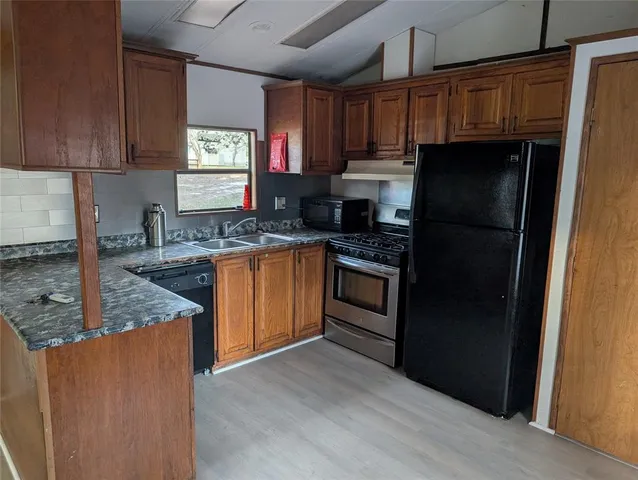 a kitchen with granite countertop stainless steel appliances a refrigerator a sink and cabinets