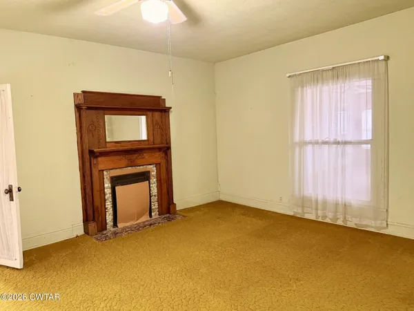 a view of an empty room with window and fire place