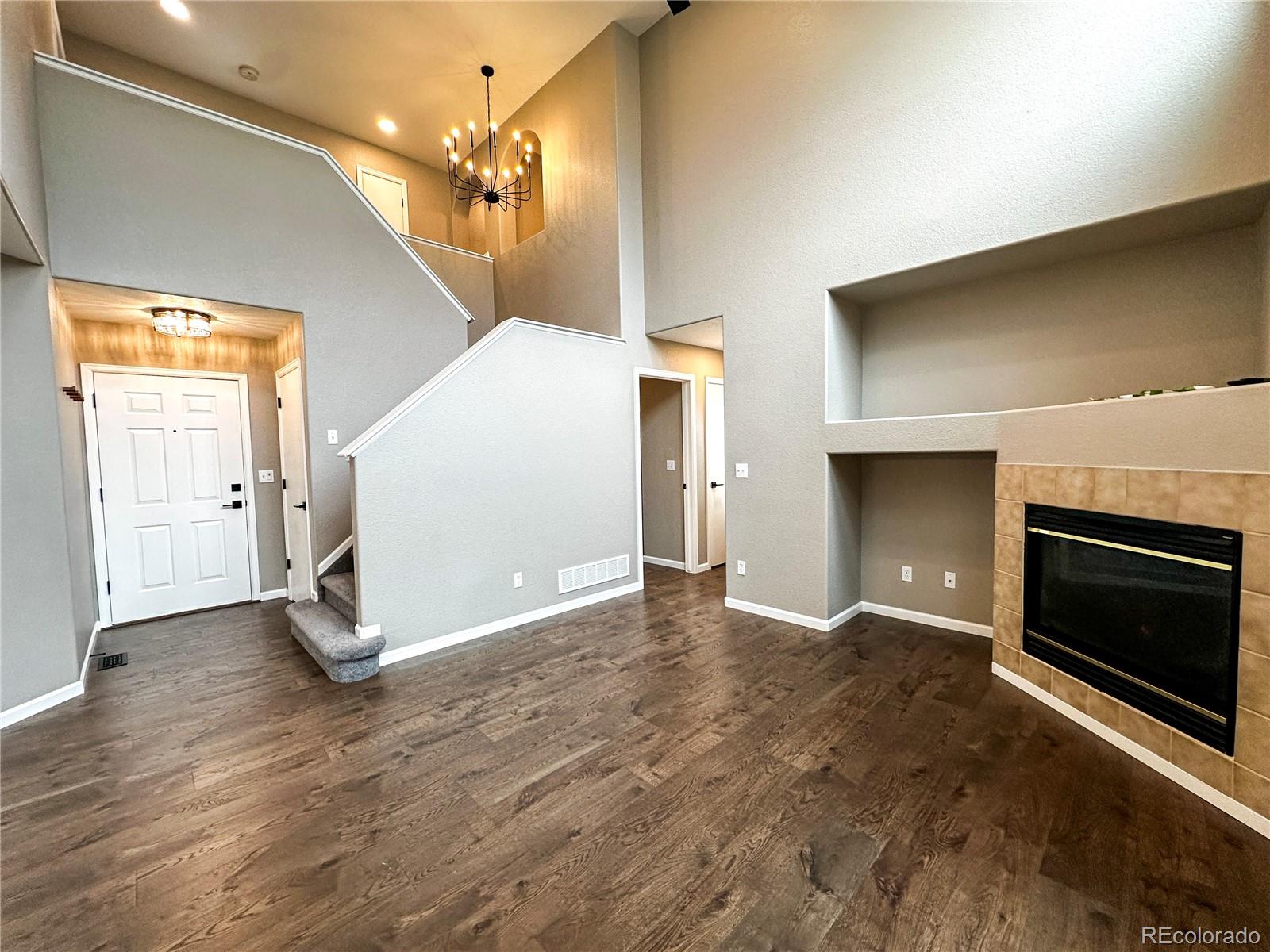 9933 Harris Street Denver, CO 80229 - Photo 4 of 25 an empty room with wooden floor fireplace and windows
