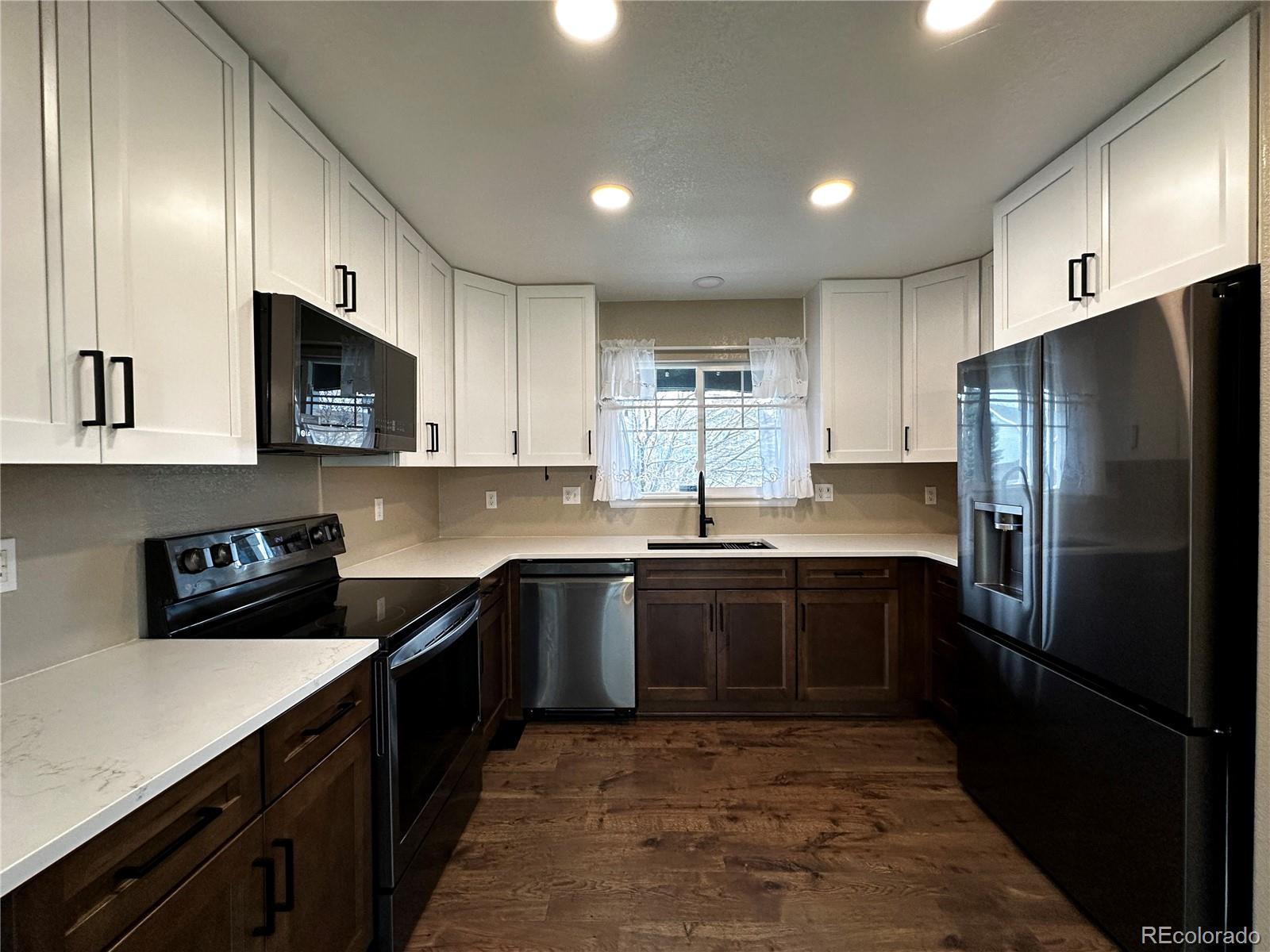 9933 Harris Street Denver, CO 80229 - Photo 7 of 25 a kitchen with stainless steel appliances granite countertop a refrigerator a sink dishwasher a stove and white cabinets