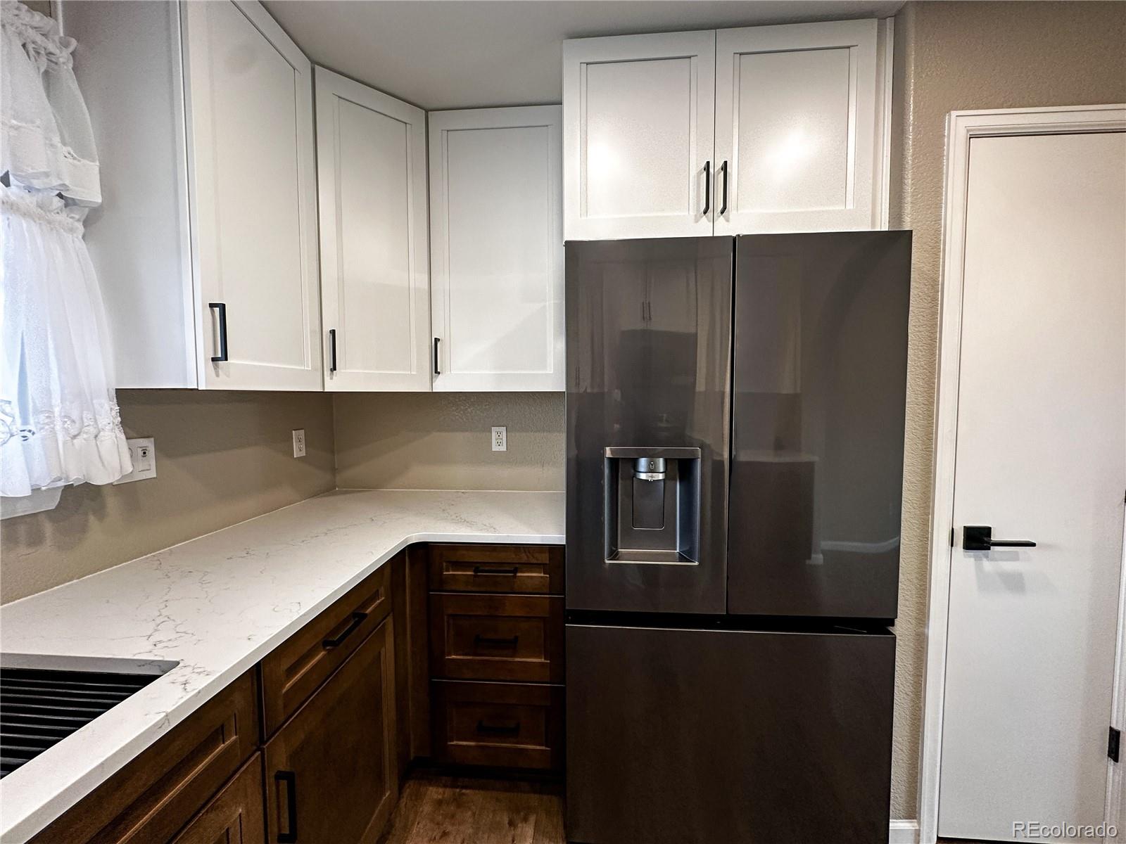 9933 Harris Street Denver, CO 80229 - Photo 9 of 25 a kitchen with a refrigerator and cabinets