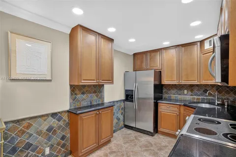 a kitchen with stainless steel appliances granite countertop a refrigerator and a stove top oven