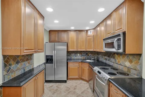 a kitchen with stainless steel appliances granite countertop a sink stove microwave and refrigerator