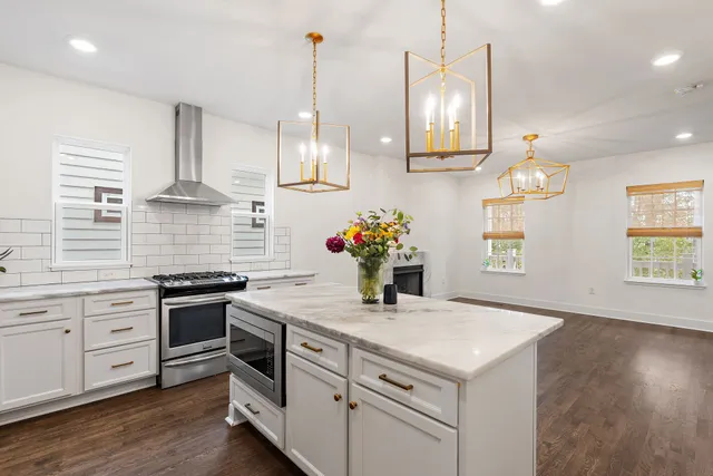 a kitchen with stainless steel appliances granite countertop a sink a stove and a wooden floor