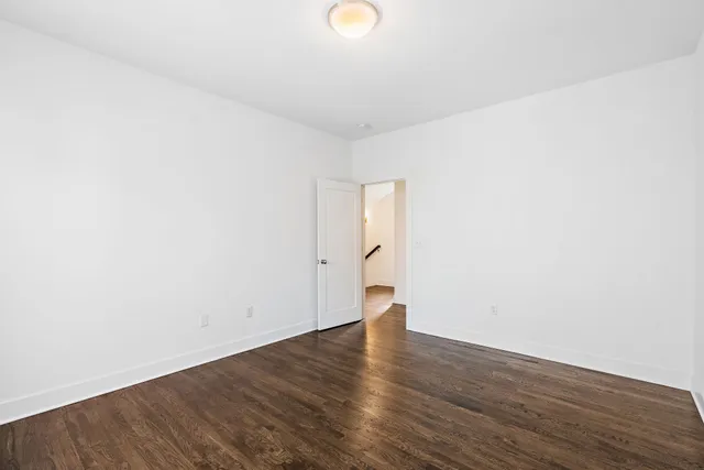 a view of an empty room with wooden floor and windows