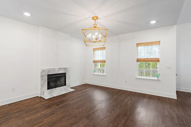 a view of an empty room with wooden floor fireplace and a window