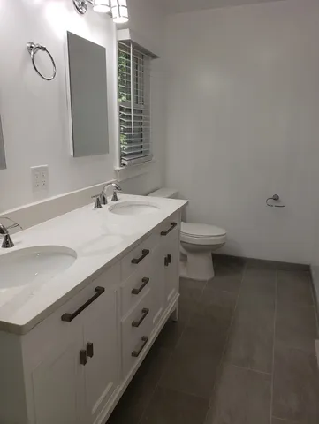 a bathroom with a double vanity sink toilet and mirror