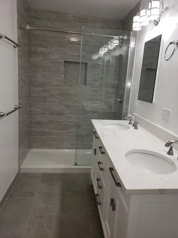 a bathroom with a double vanity sink a large mirror and shower