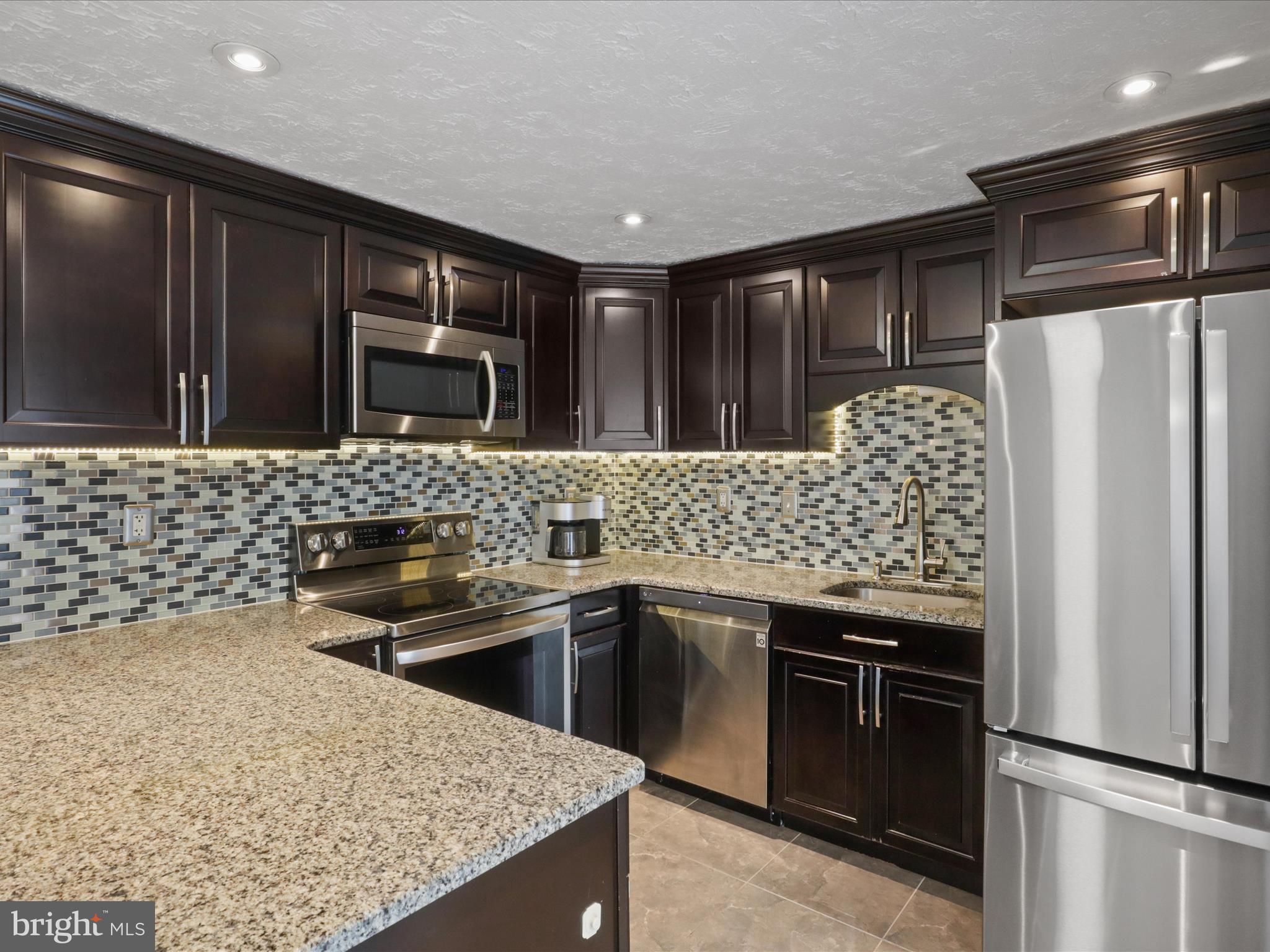 7313 Husky Lane Springfield, VA 22151 - Photo 14 of 49 a kitchen with stainless steel appliances granite countertop a sink stove and refrigerator