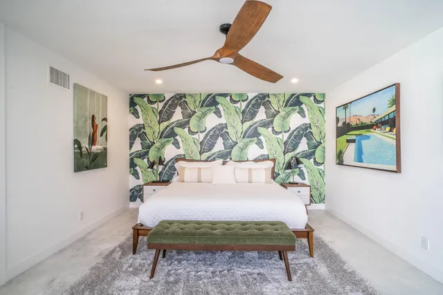 a view of a white house next to a yard with plants and trees