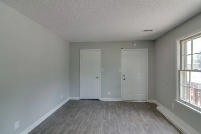 an empty room with wooden floor and windows