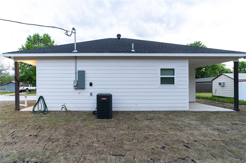 839 Southwest 7th Street Cooper, TX 75432 - Photo 11 of 21 Rear view of property featuring a yard, central air condition unit, and a shingled roof