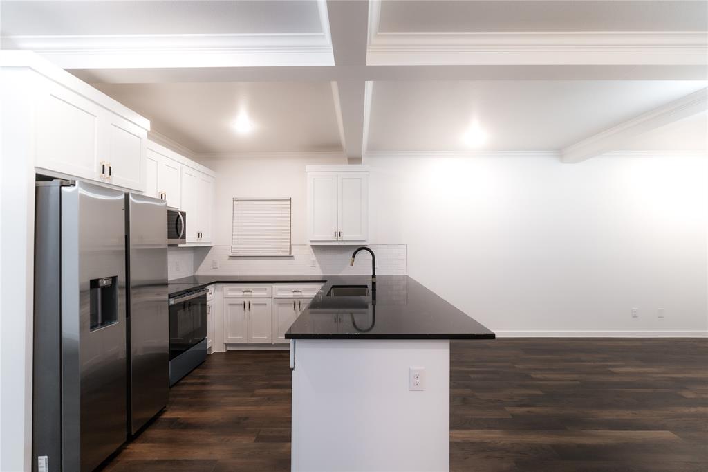 839 Southwest 7th Street Cooper, TX 75432 - Photo 18 of 21 Kitchen with dark wood-style floors, a sink, stainless steel appliances, a peninsula, and dark countertops