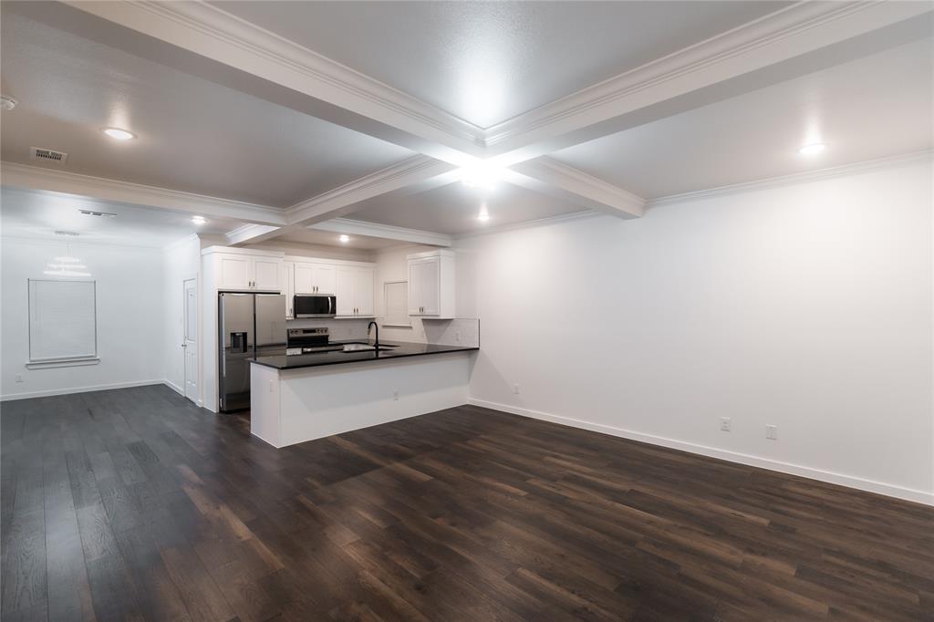 839 Southwest 7th Street Cooper, TX 75432 - Photo 3 of 21 Kitchen featuring dark wood-style floors, crown molding, a peninsula, dark countertops, and appliances with stainless steel finishes