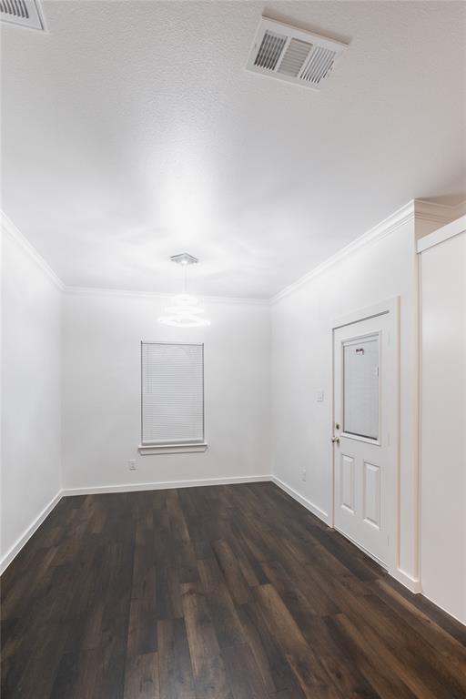 839 Southwest 7th Street Cooper, TX 75432 - Photo 9 of 21 Spare room featuring dark wood-style floors, visible vents, crown molding, and baseboards